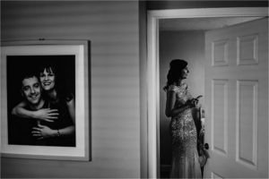 Bridesmaid through a doorway with a portrait of Bride's parents on the wall