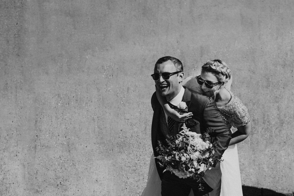 Bride and groom laughing as the bride climbs on the grooms back