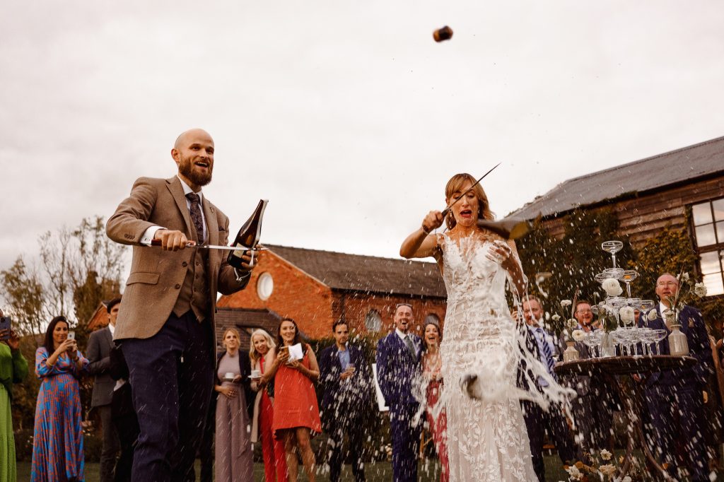 Bottle of champagne smashing as Bride opens it with a sabre