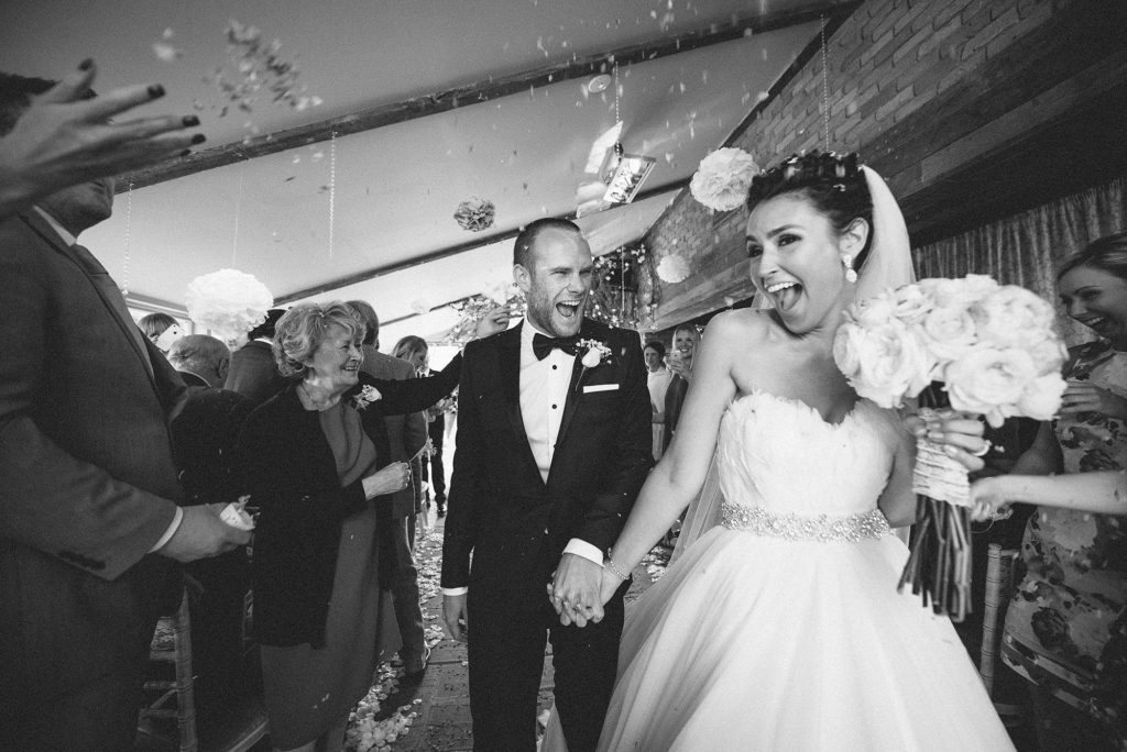 Bride and groom laughing as the walk up the aisle together holding hands.