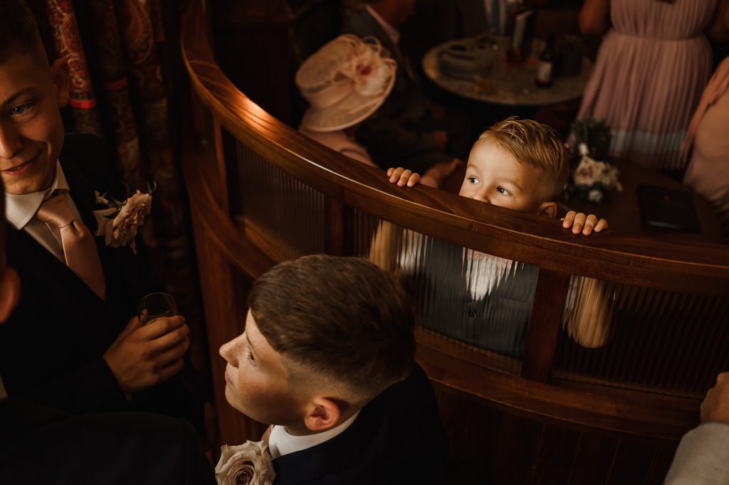 Young Wedding Guests peeks over the back of a seat