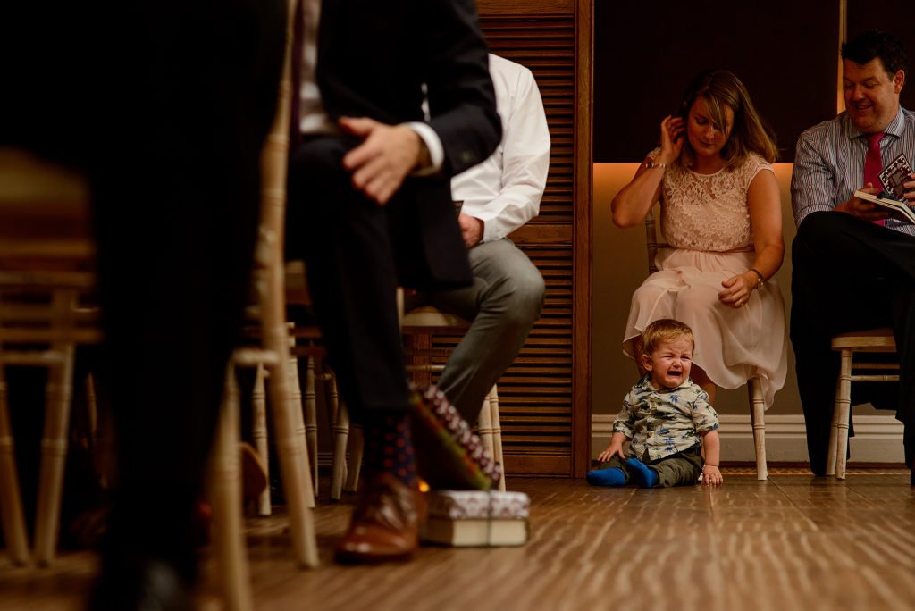 Child sat on the floor, crying during the wedding ceremony