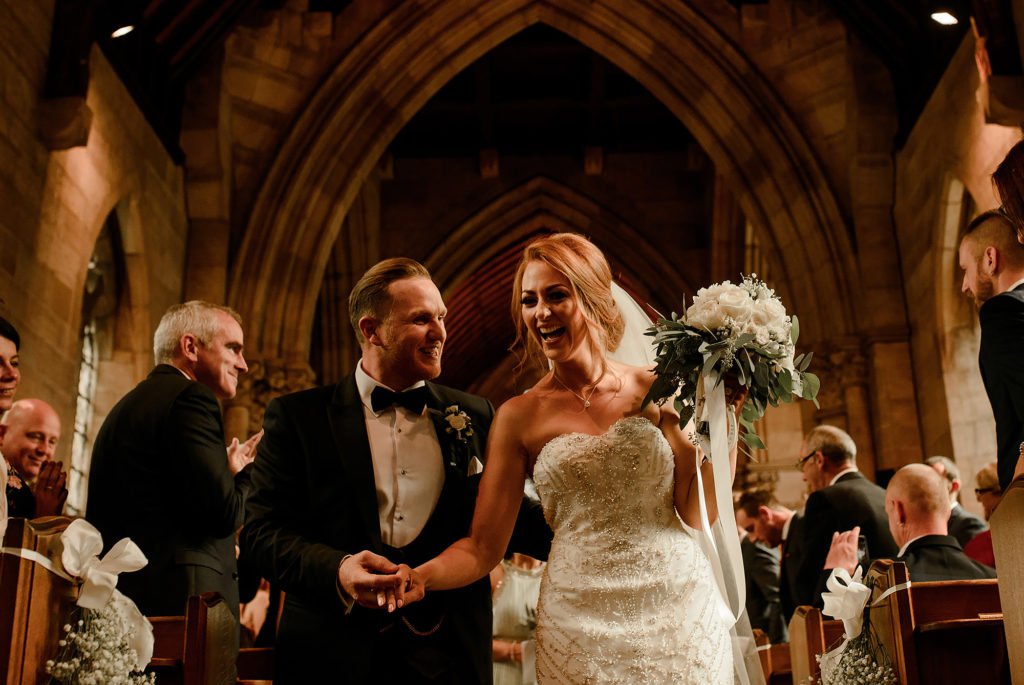 Bride and Groom laughing as the walk up the aisle after their wedding ceremony