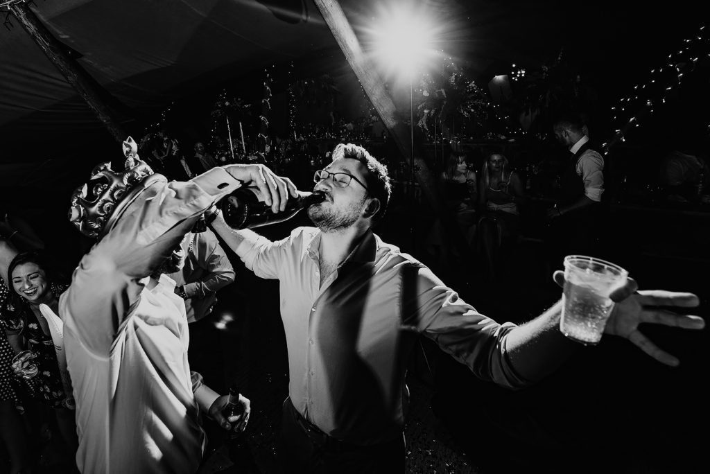 Wedding Guest getting champagne poured into his mouth on the dance floor