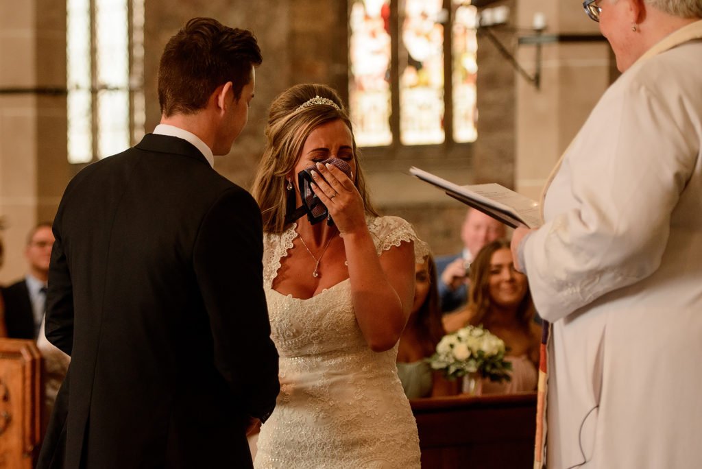 Bride covering her face as she cries during the wedding ceremony