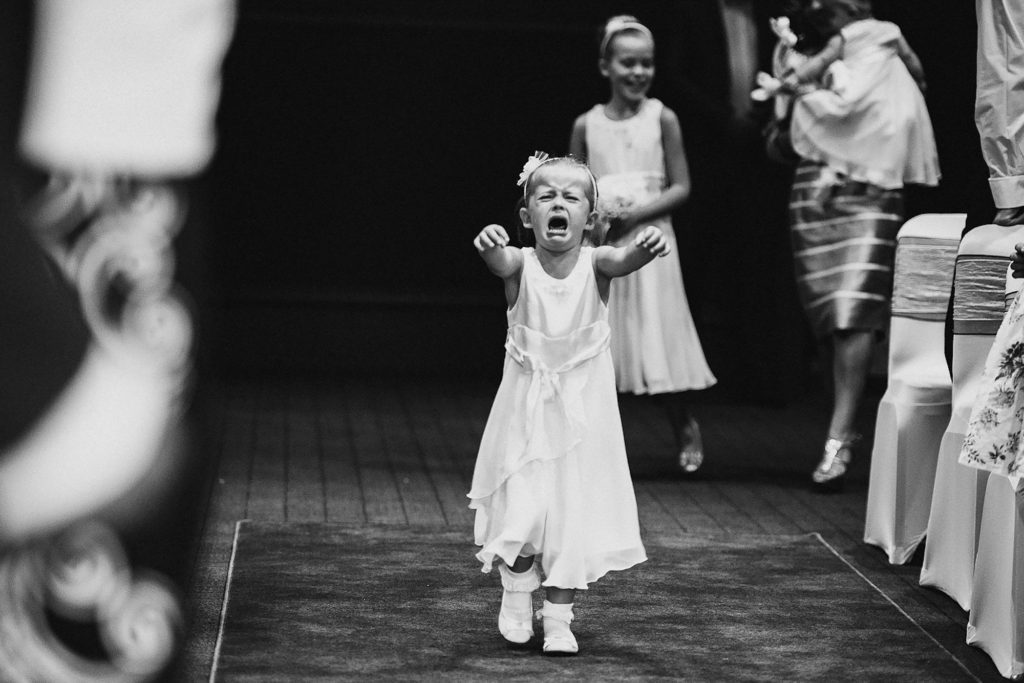 Flower girl crying as she walks up the aisle for the wedding ceremony