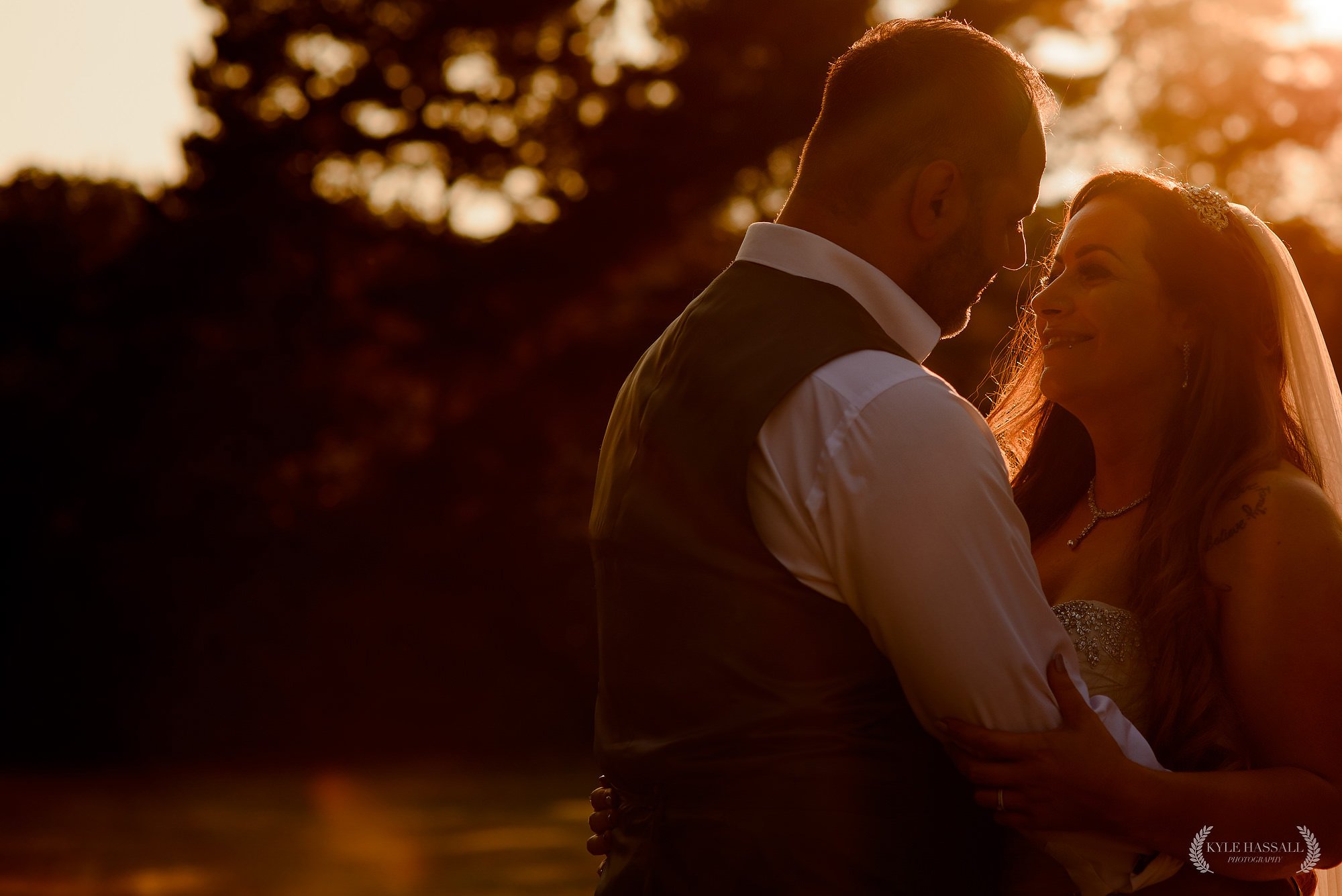 Bride and Groom stood close together in beautiful golden light