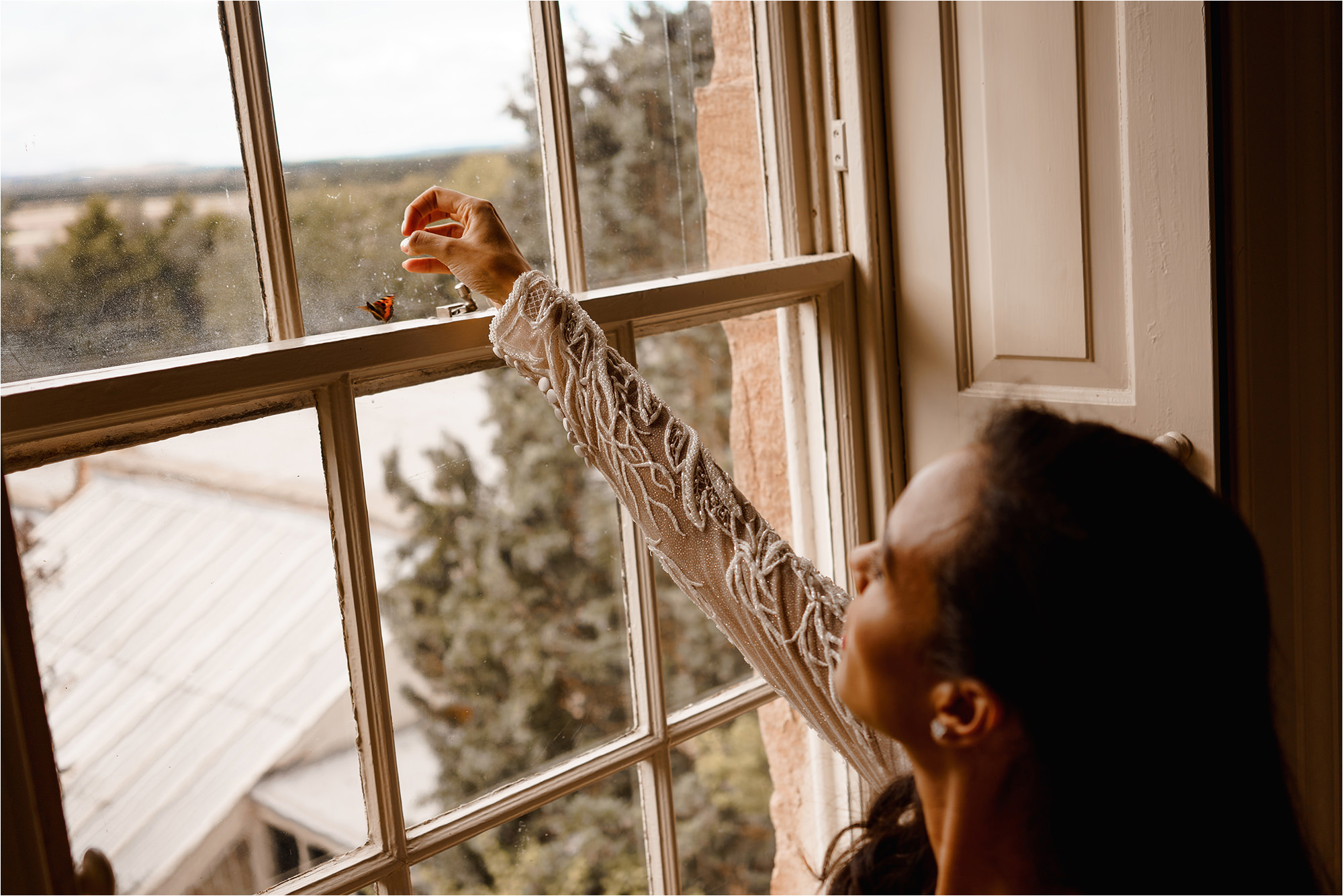 Bride rescuing a butterfly on a window