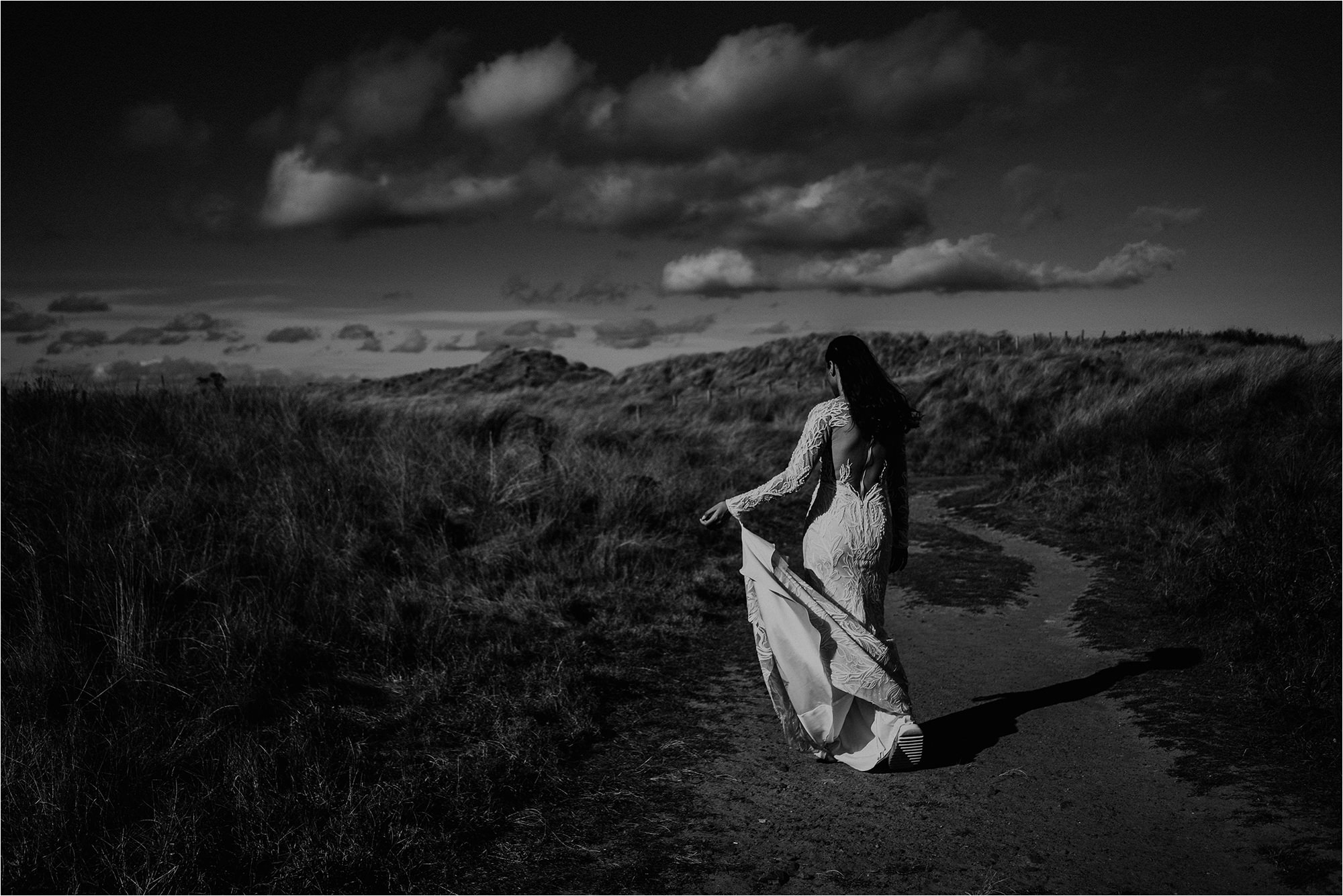 Bride walking down a path to a beach