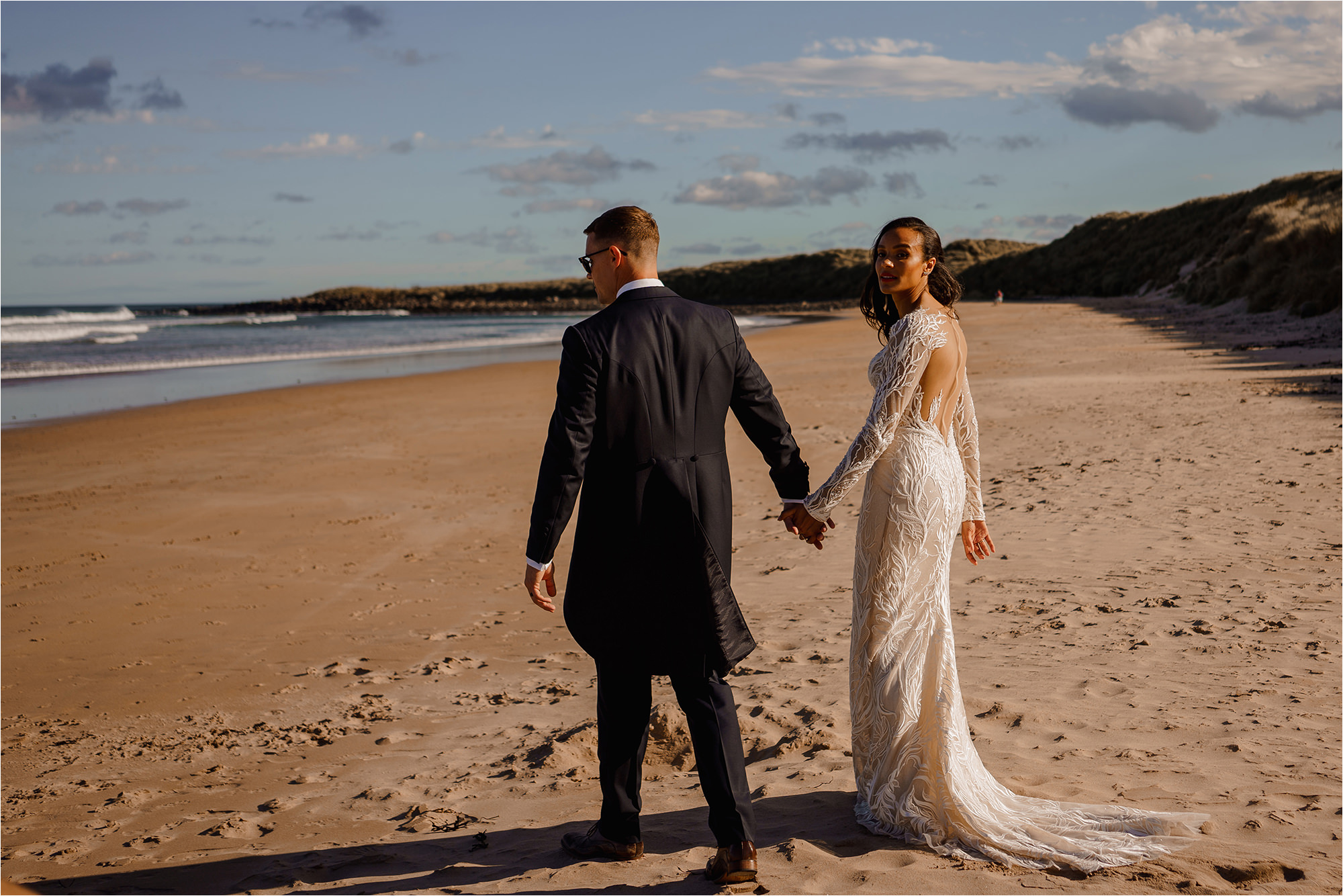 Bride and Groom holding hands and walking along a beach