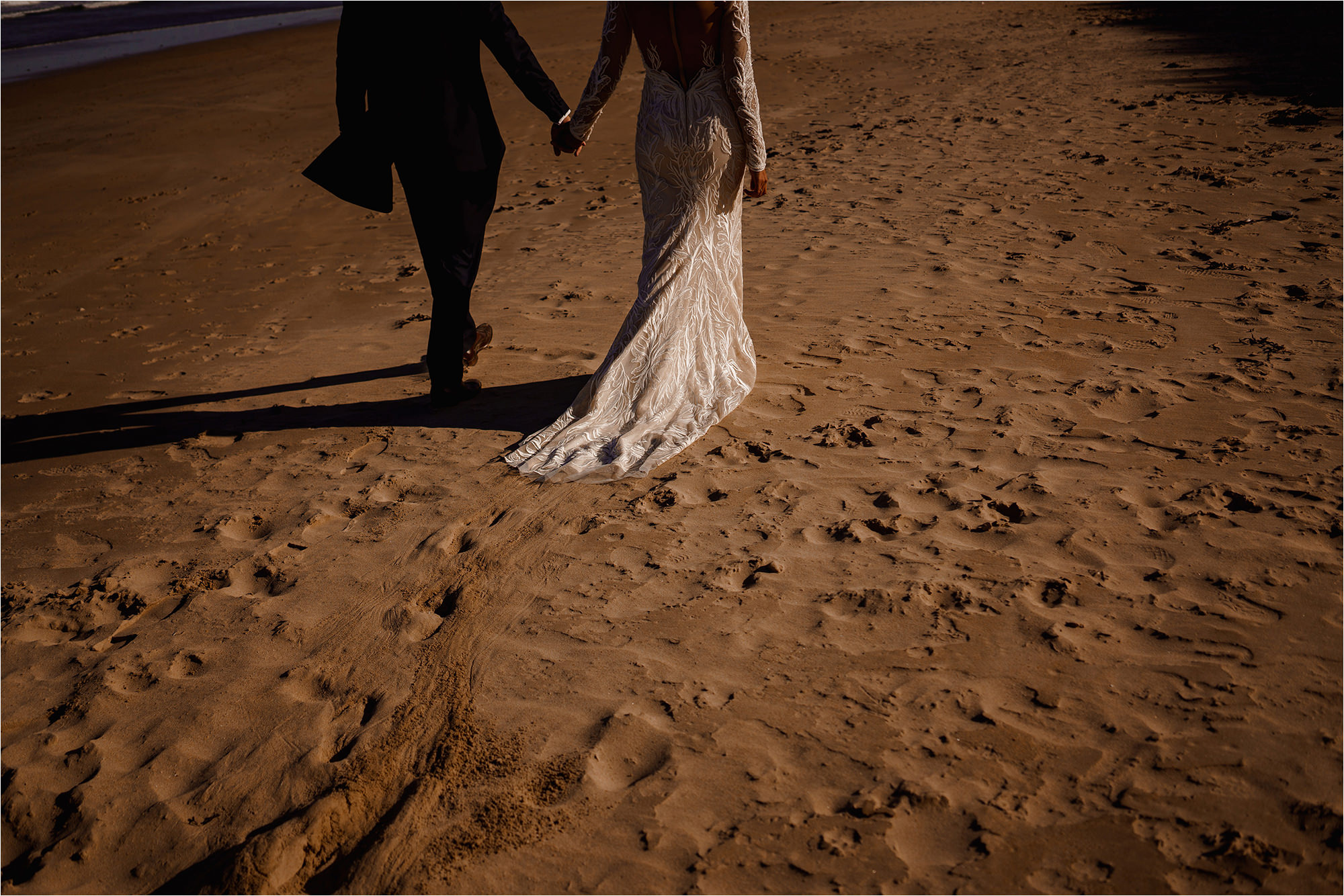 Photograph of the Bride and Groom walking along the beach