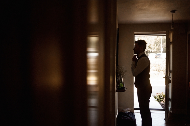 Silhouette of Groom tying his tie