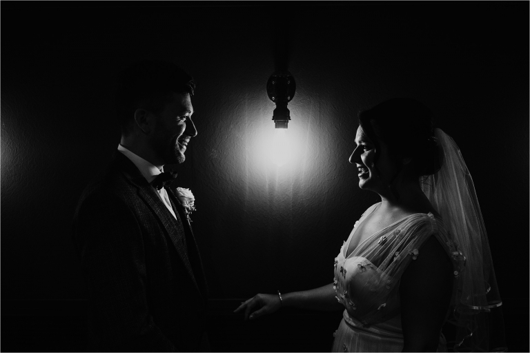 Bride and Groom facing each other, lit by single lightbulb