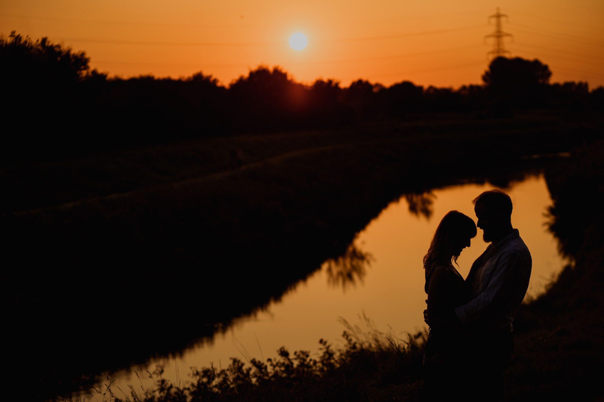 Silhouette of couple in reflection of river