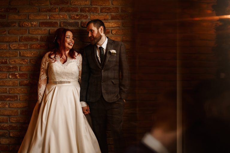 Bride and Groom stood next to a window