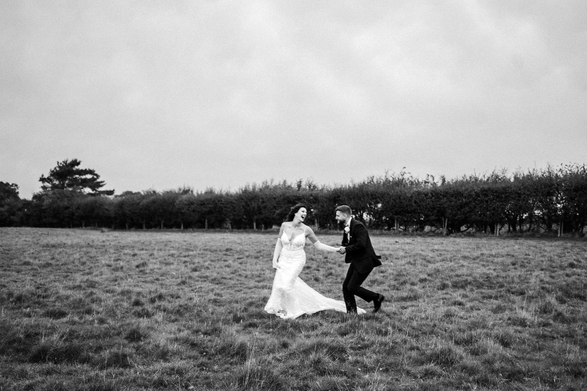Bride and Groom walking across a field and laughing
