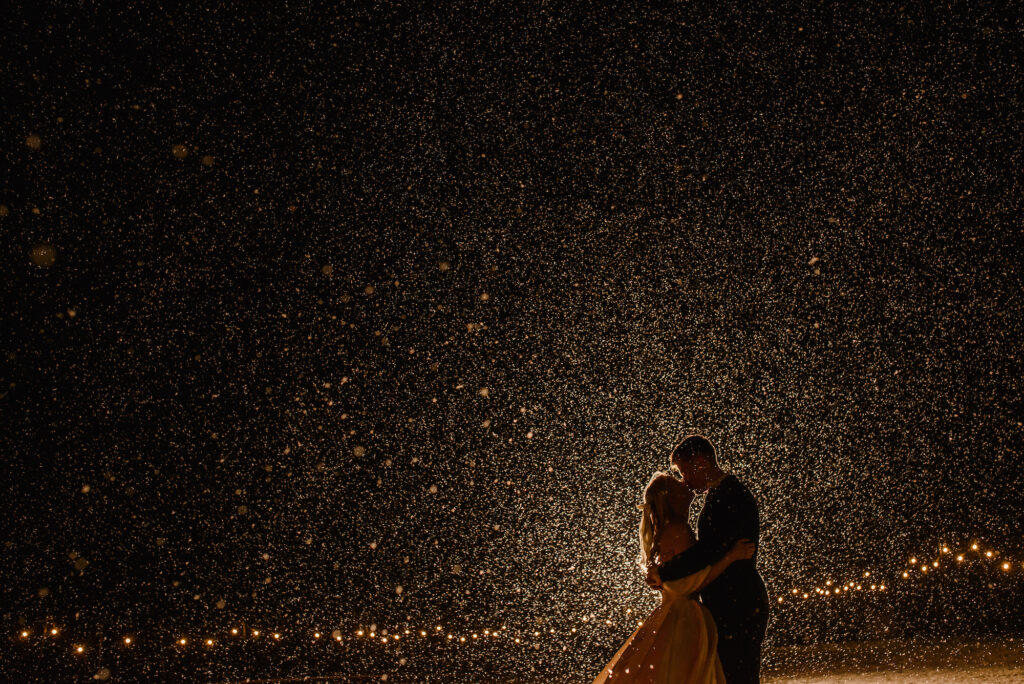 Bride and groom kissing in the rain